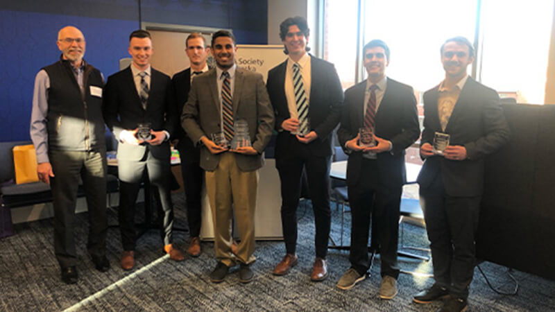 Students gather for a photo with professor at case competitions site.