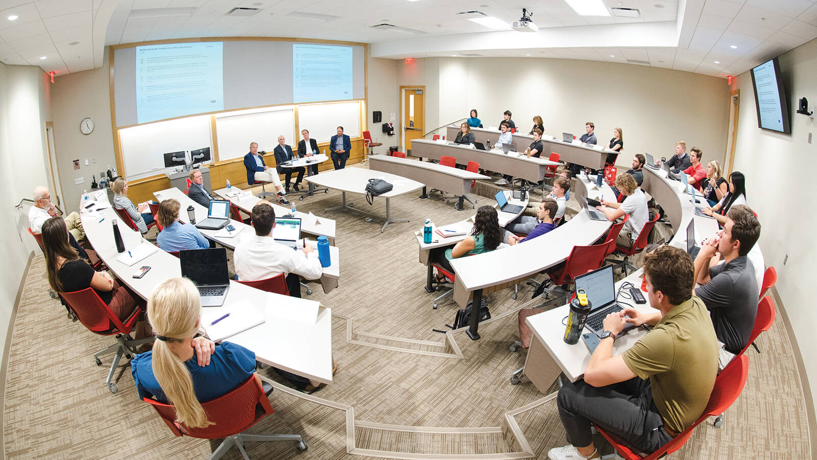 Students in a finance classroom attend to a presentation from fellow students.