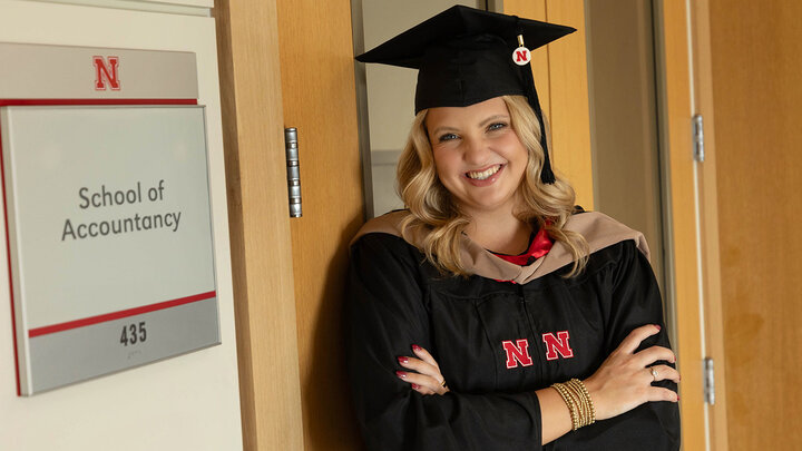 Elli Richardson standing next to School of Accountancy in cap and gown