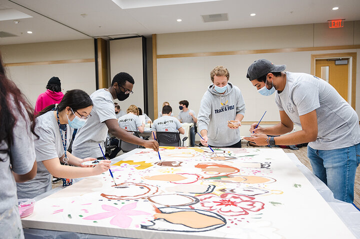 Luis De La Torre (far right) joined other business students in painting the DIGS mural. He saw the painting event as a way to meet new people.