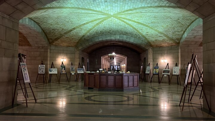 An art exhibit with posters on easels around the first floor rotunda of the Nebraska State Capitol, illuminated by blue-green light