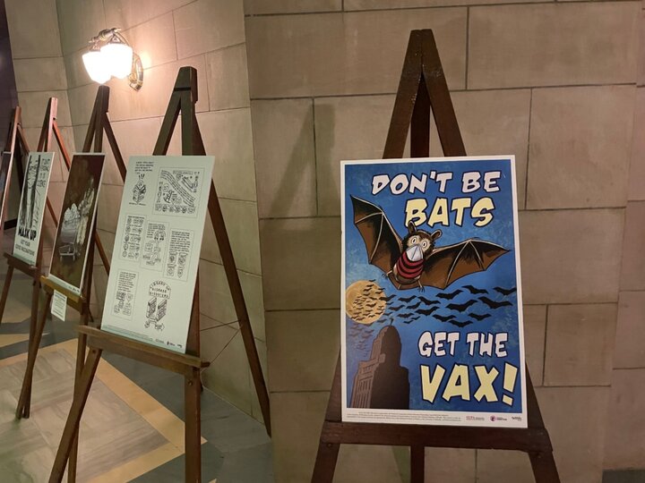 Pro-vaccination posters on easels against a stone wall