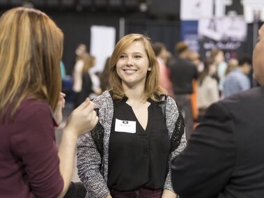 Student engaging with two recruiters at a career fair
