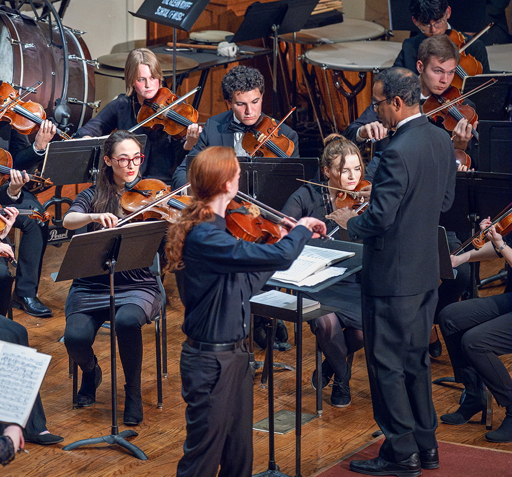 An orchestral ensemble performs on stage.