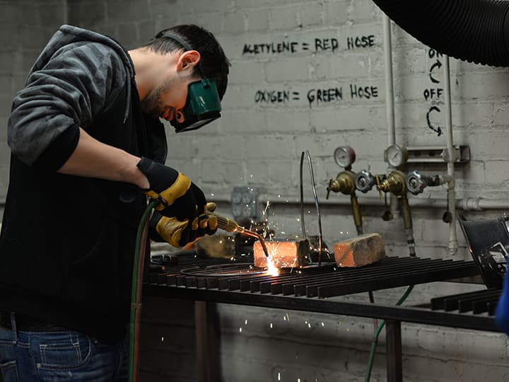 A student welds pencil rod into a form.