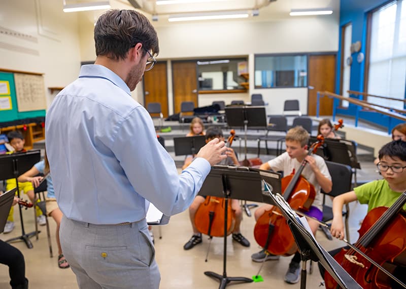 A conductor instructs child musicians.