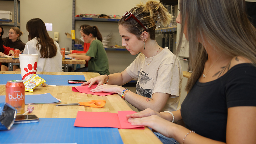 Members of the Creative Commons Club sit at tables crafting art.