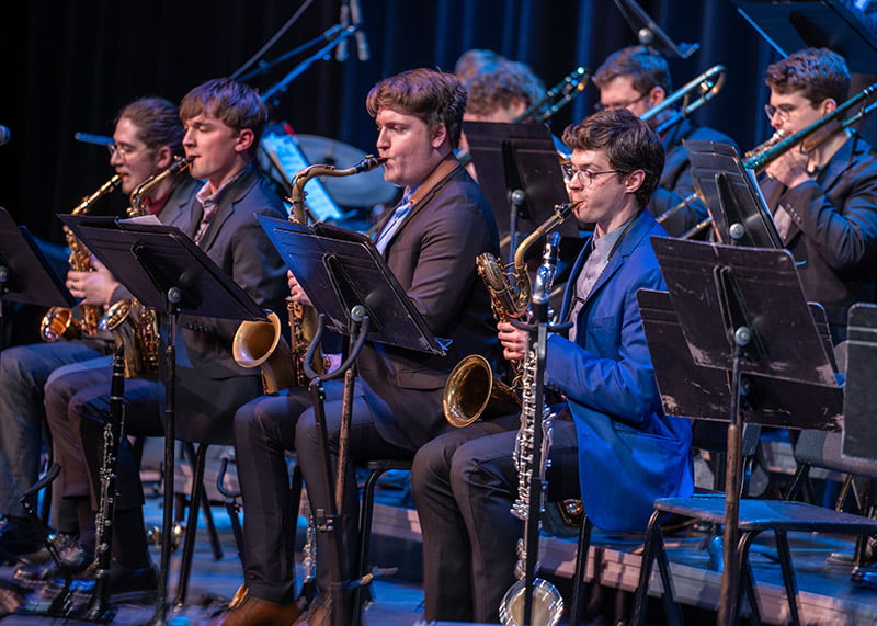 Musicians in suits play on stage.