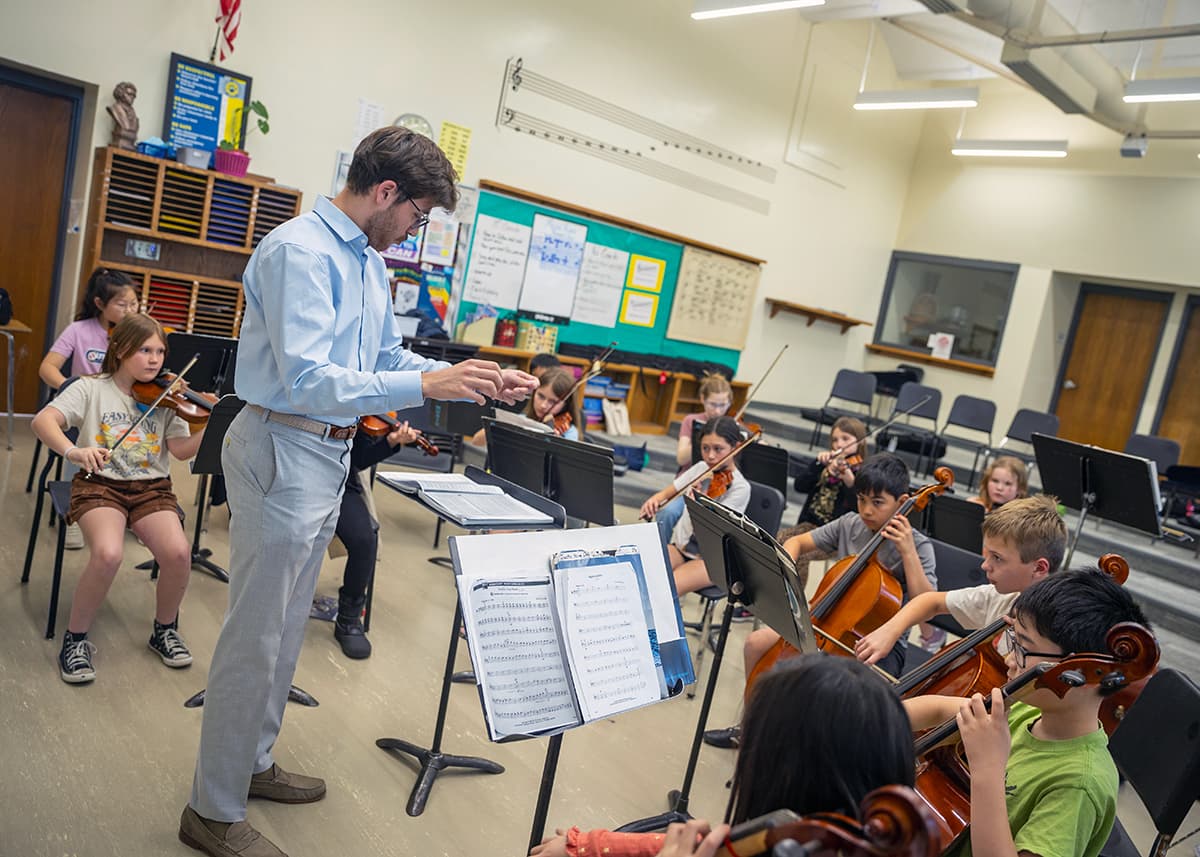 A conductor instructs child musicians.