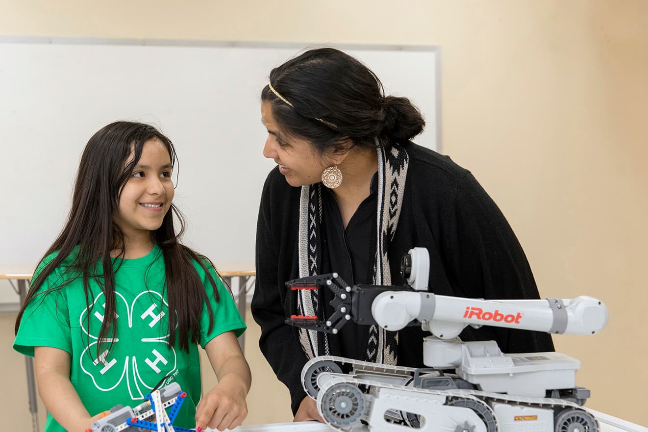 Adult helping youth with STEM robotics project. 