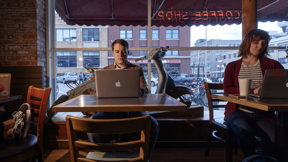 Man works at a computer in a coffee shop