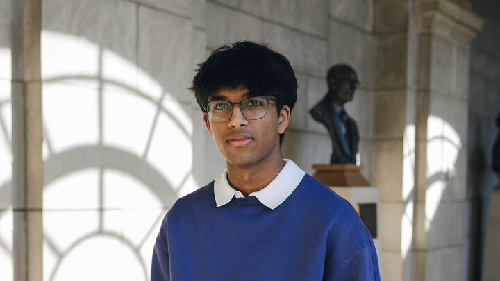 Student standing in hallway of state capitol by bronze bust