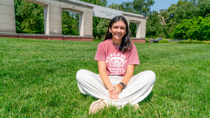 Student sitting cross-legged in grass in Coryele Common Area
