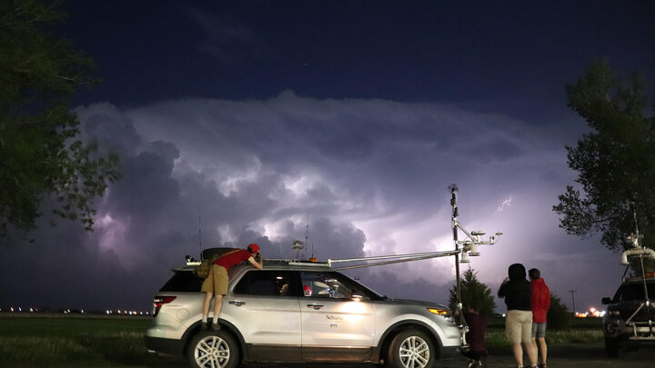 Students and faculty standing outside of atmospheric research vehicle ahead of incoming storm