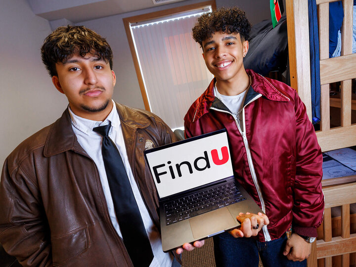 Two students in Raikes School holding laptop with custom application displayed on screen