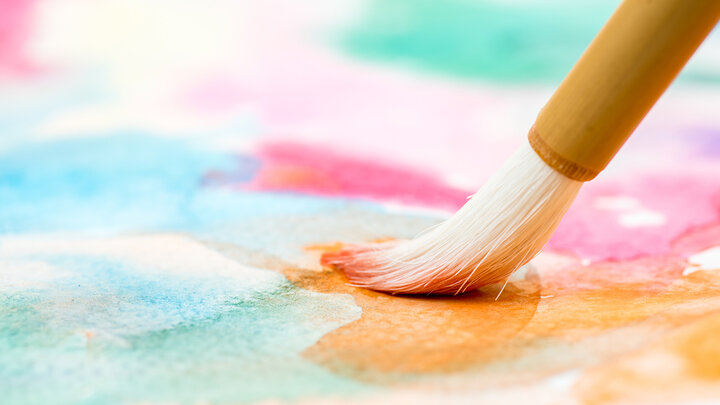 Brush painting vibrant watercolor strokes on paper.