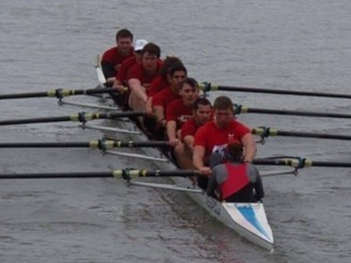 A rowing shell of 8 mens members rowing.
