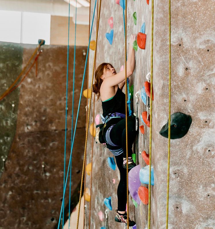 A young woman climbing a rock wall