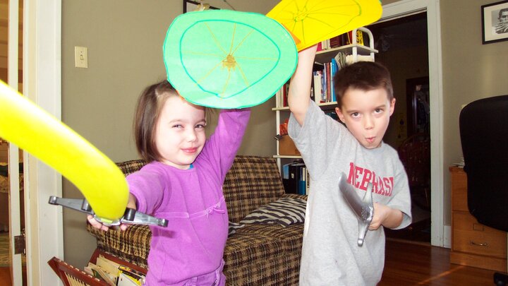 Kids in pajamas with toy swords in an 'en garde' pose