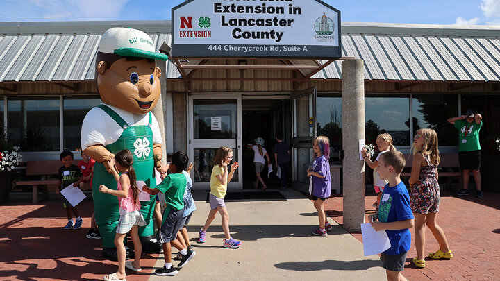 4-H mascot greeting youth in front of building