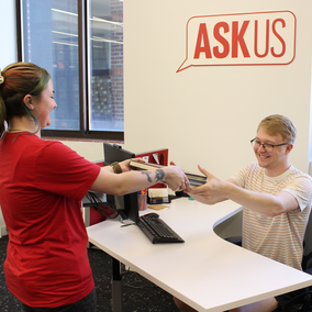 student returns books to an askus desk.