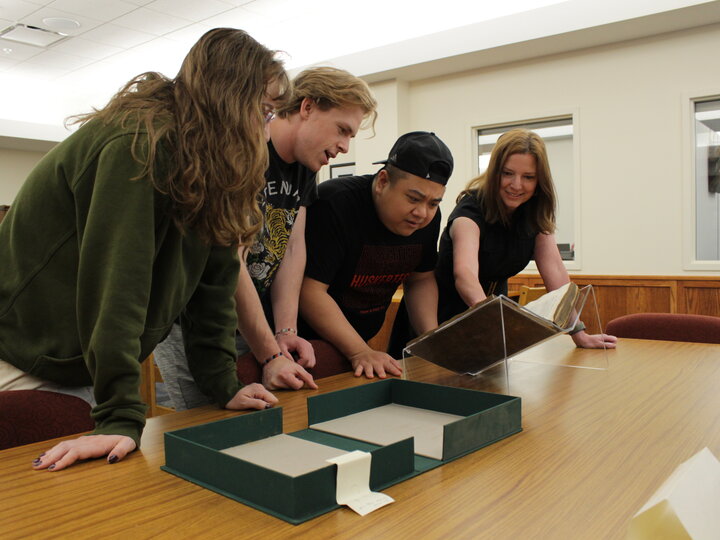 Students looking at archives materials with Librarian Traci Robison