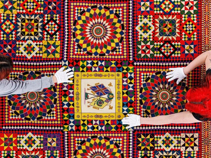 Photo of 2 students preparing a quilt for display