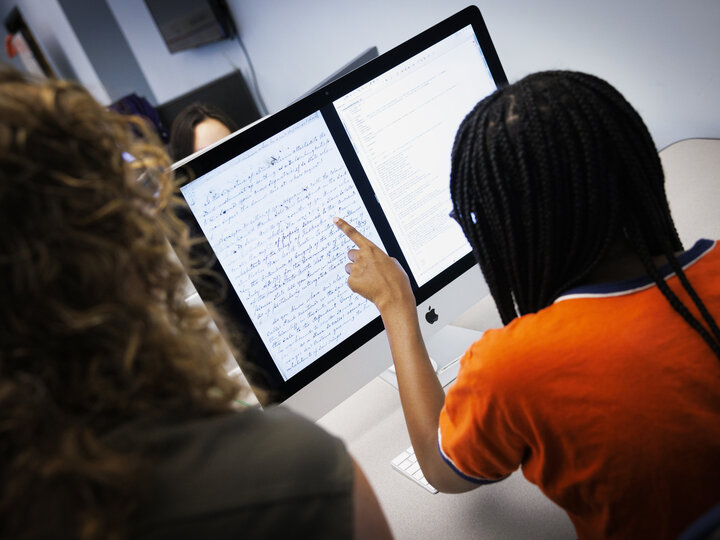 Student pointing at a computer screen at a handwritten note.