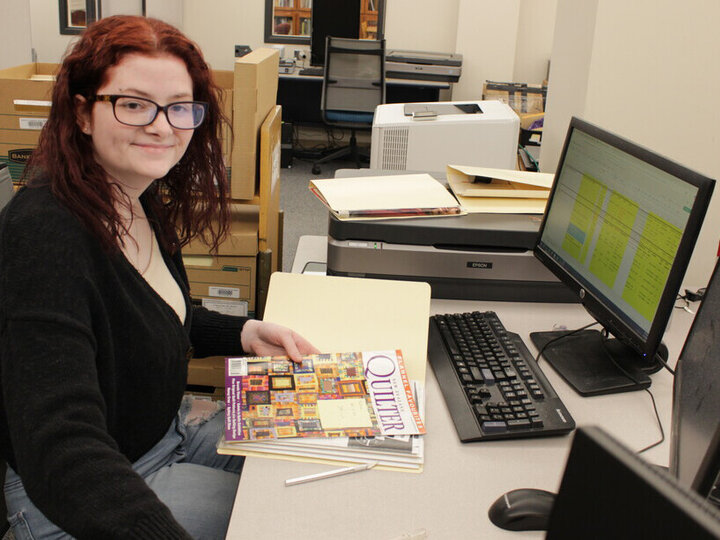 student Kierra Dunnam at desk with computer and quilter magazines